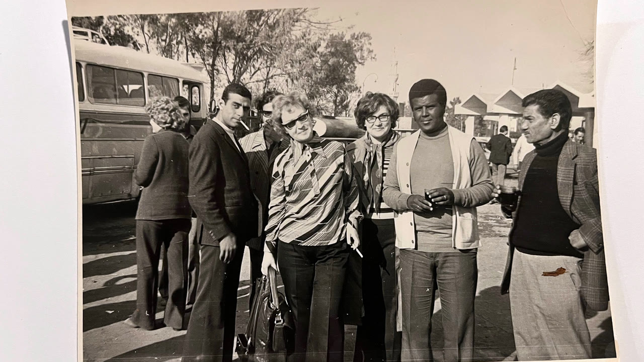 A group of young people outdoors by buses, 1960s